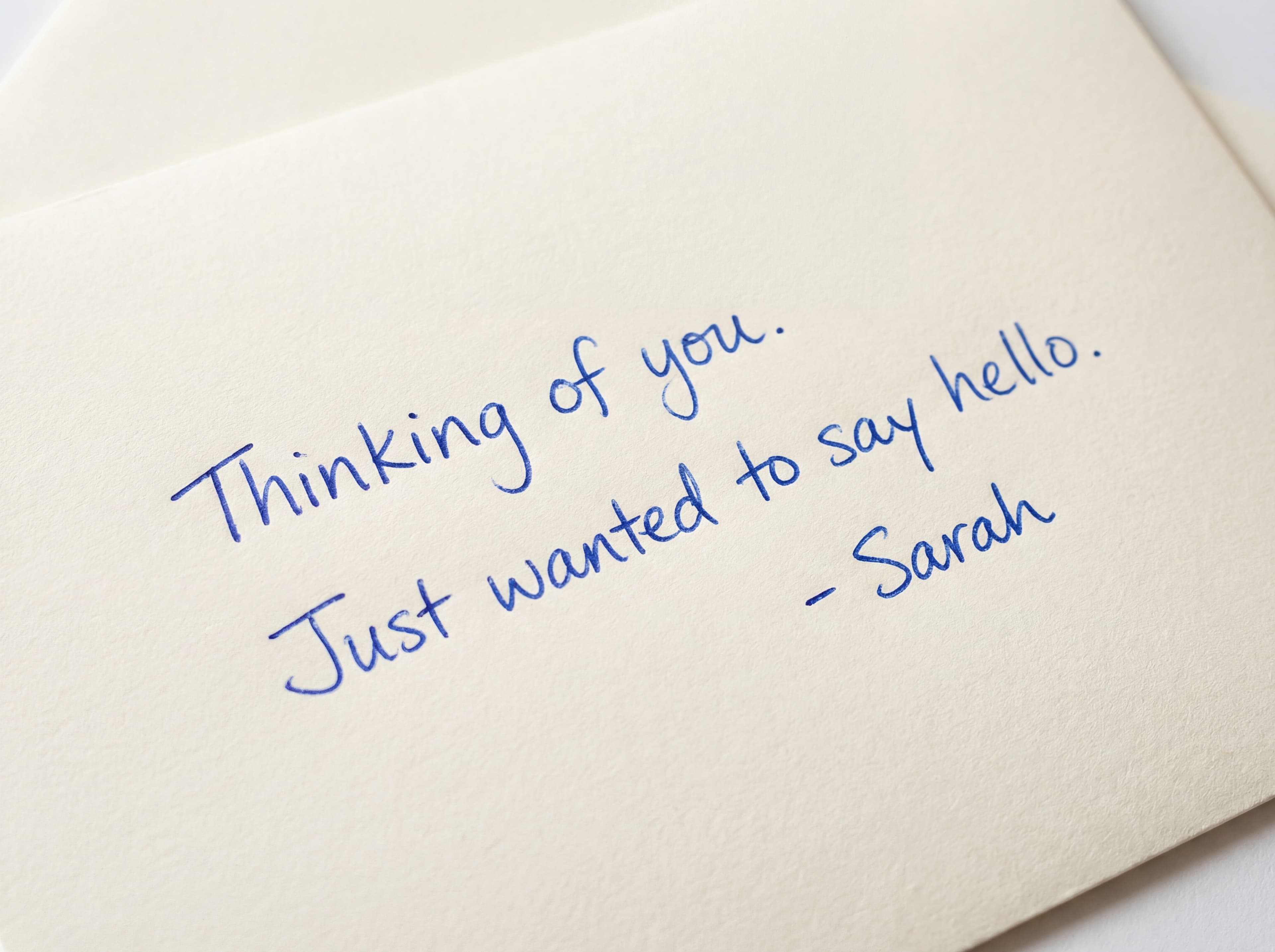 Close-up of blue pen handwriting on premium card stock